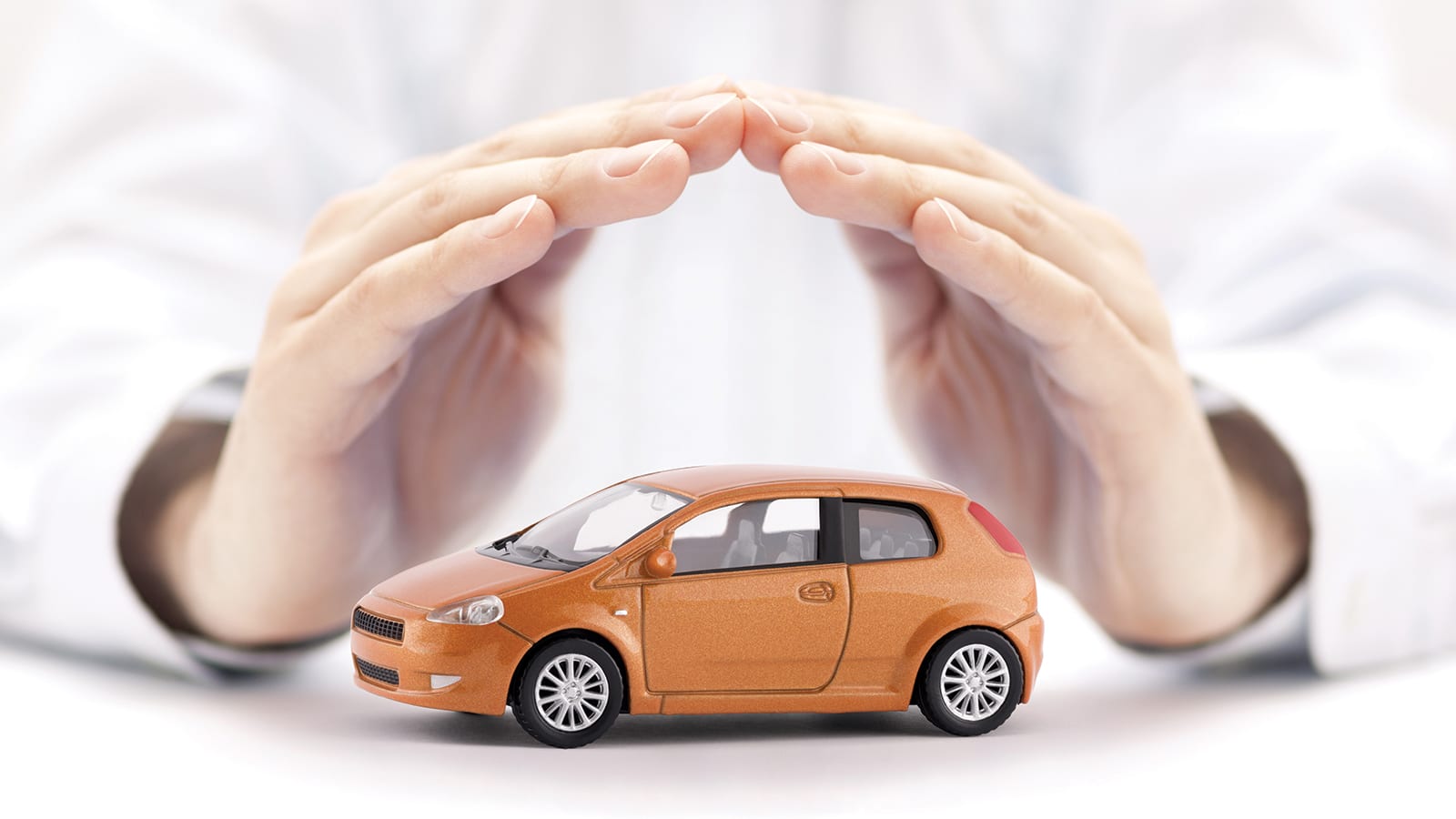 Pair of hands forming a roof over range toy car