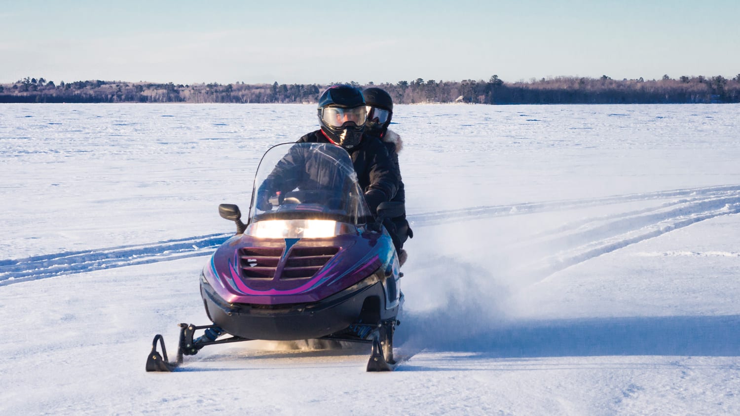 two people riding a snowmobile on snowy plain in Yellowknife
