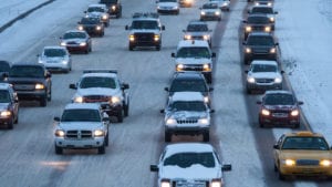 snow-covered cars practicing safe winter driving on four-lane highway