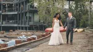 married couple walking on dock in front of lakeside restaurant at intimate alberta wedding
