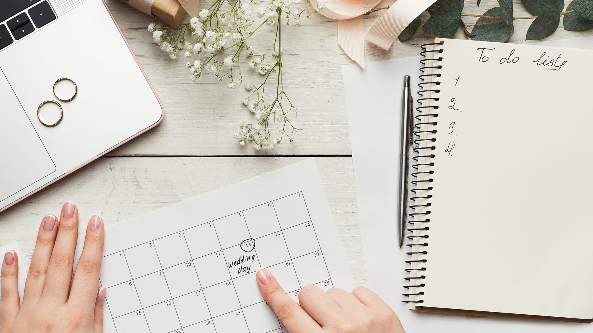 top-down image of woman's hands point to calendar and to-do list planning an intimate alberta wedding