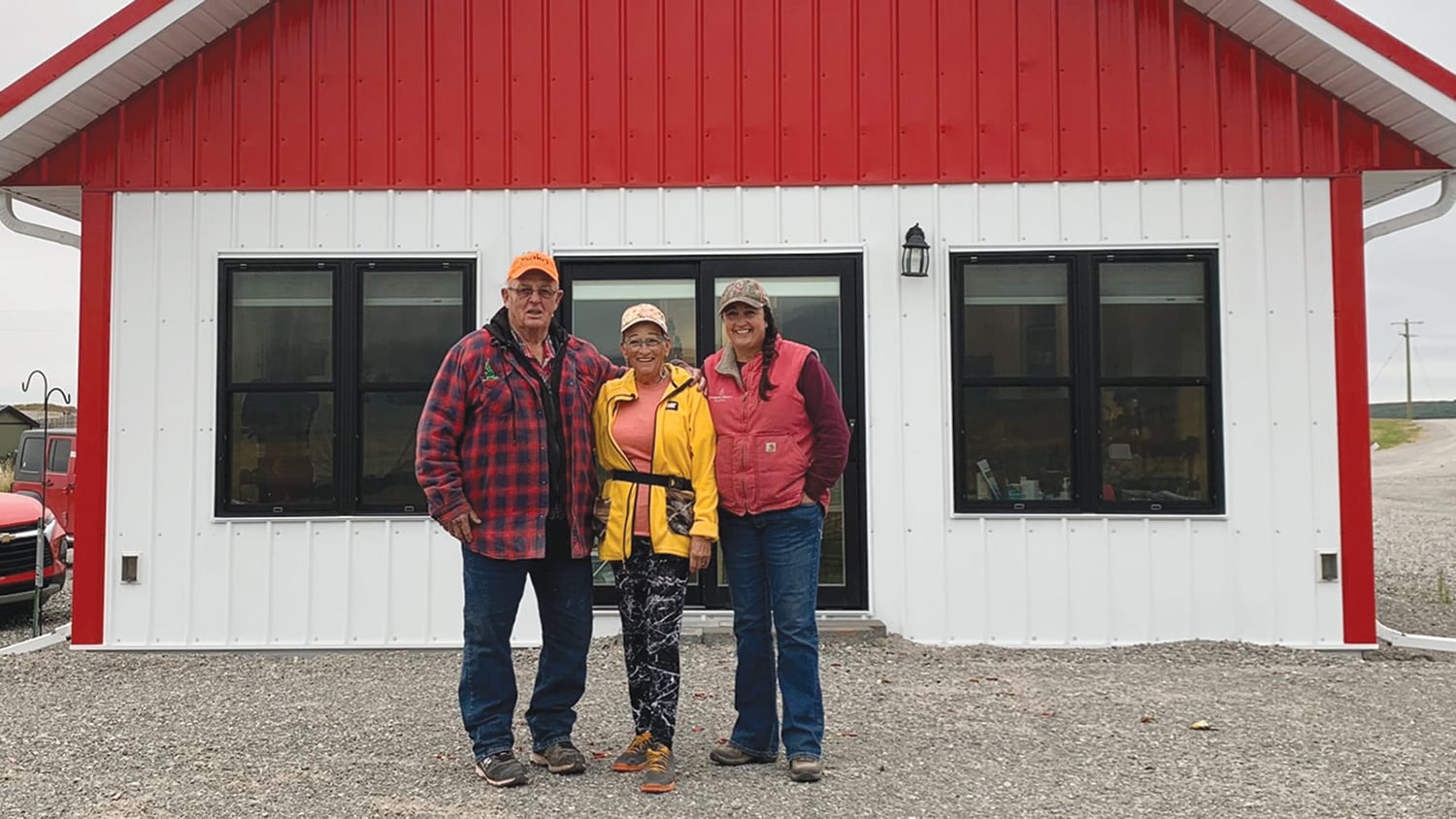 three members of family standing in front of building with white and red facade in waterton