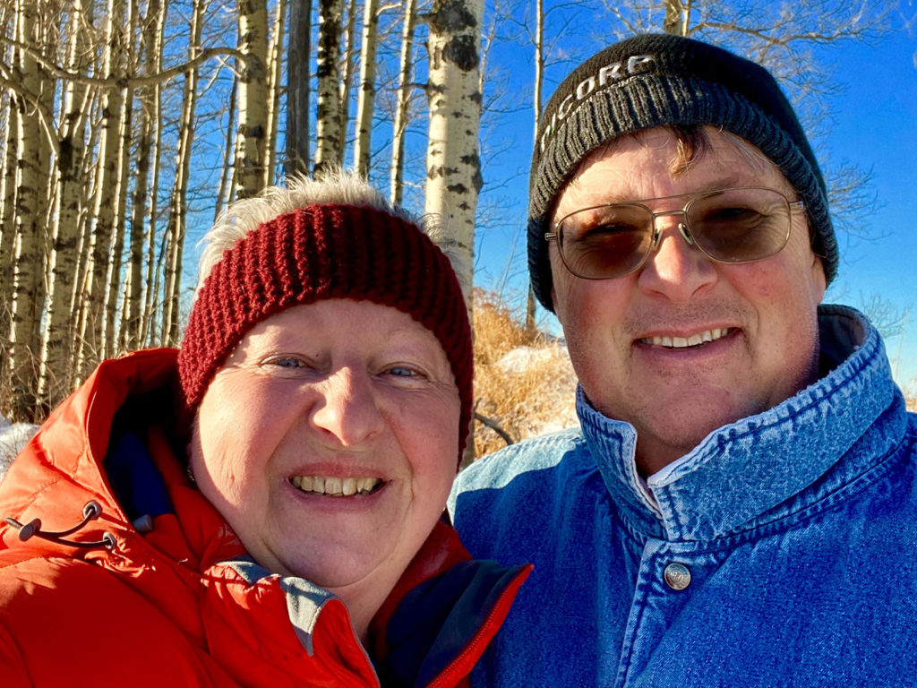 Smiling older couple wearing winter clothes in a birch forest