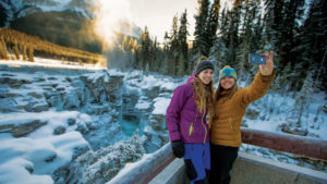 Two women taking selfie in front of Athabasca Falls in Jasper National Park