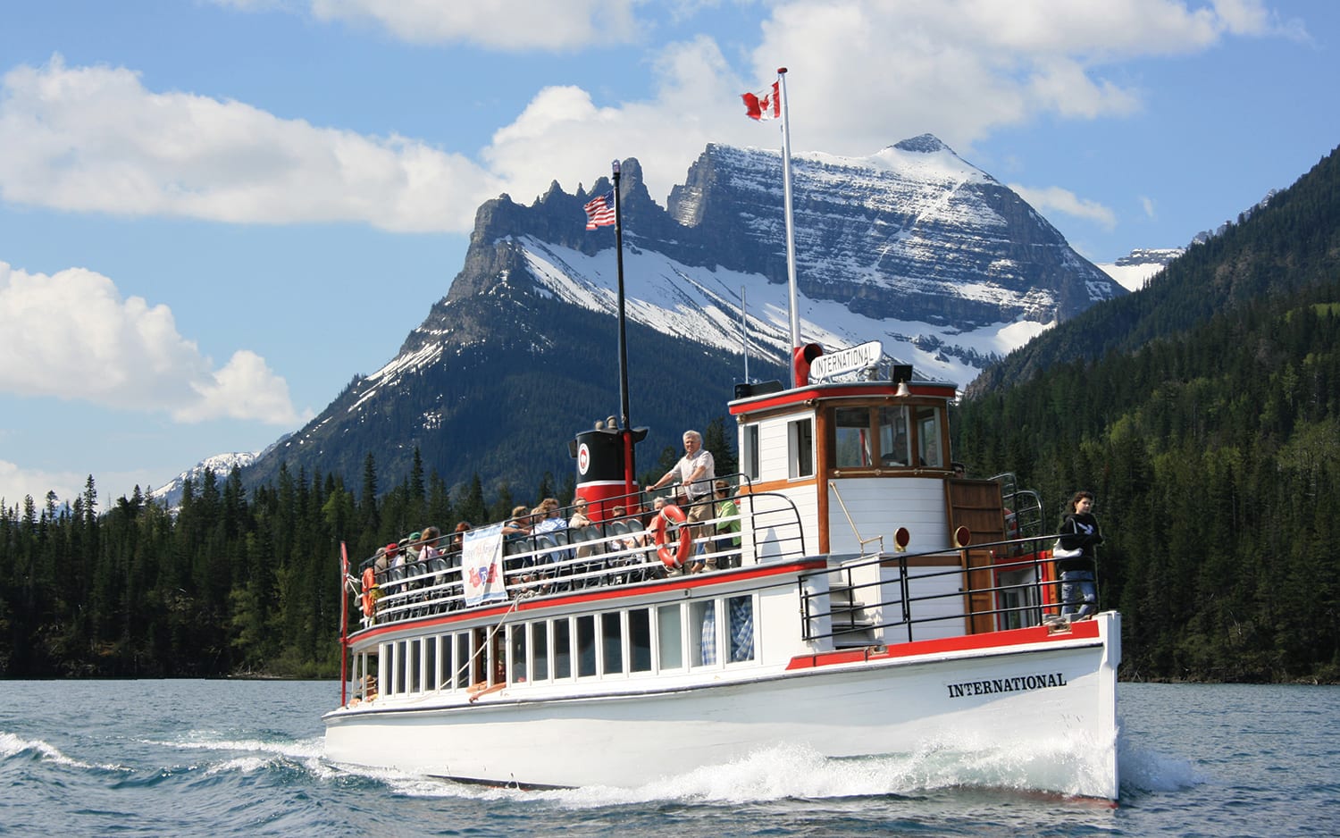 old-fashioned white boat in Waterton lake with mountain in background