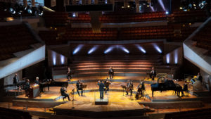 Wide-angle shot of physically distanced chamber ensemble doing a virtual performance for empty auditorium