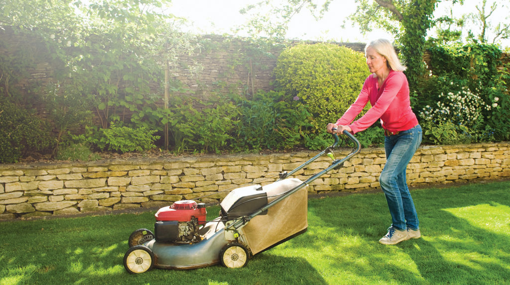 Older woman pushing gas lawnmower to help maintain her dream backyard
