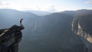 Man standing on precipice of cliff with deep valley below in adventure documentaries Free Solo