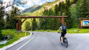 cyclist riding on Bow Valley Parkway toward entrance archway