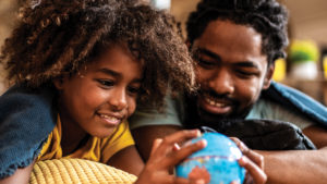 Smiling father and son looking at small globe as they contemplate post-covid travel