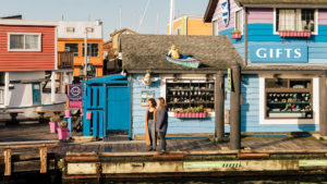 two women standing on dock in front of colourful harbour houses in Victoria B.C.